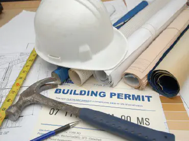 hard hat, hammer and building blueprints on a desk