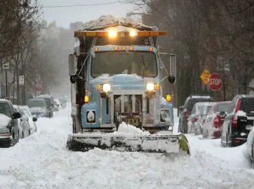 A City of Chicago snow plow clearing a road filled with heavy snow.