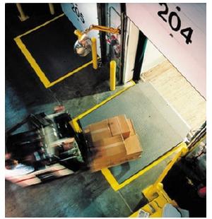 Forklift driving over a dock leveler