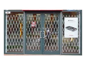 A folding gate protecting the entrance to a retail store.