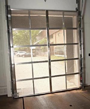 A garage door with a heavy metal screen door.